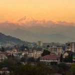 Dehradun news city skyline with snow-capped Himalayan mountains in background