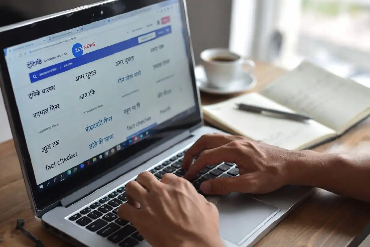 Person fact-checking Hindi news on laptop with multiple tabs open showing news sources