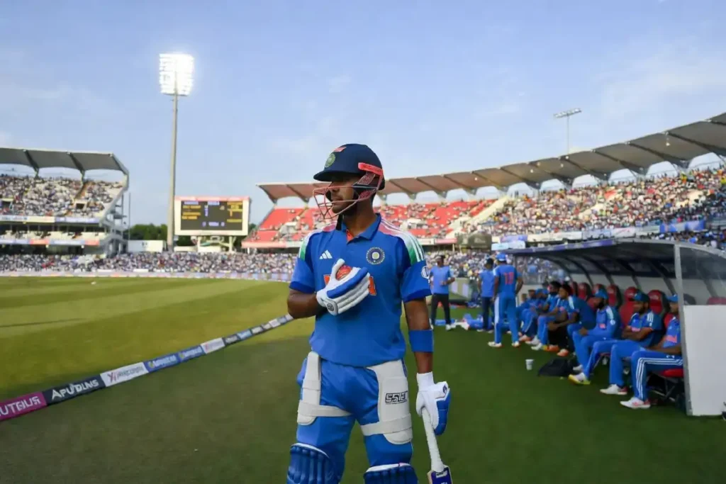 Young Indian cricketer walking out to bat at a large cricket ground